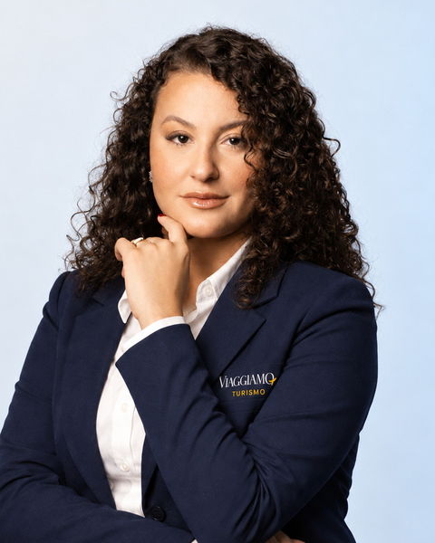 Emilly, fundadora e diretora comercial da Viaggiamo, de blazer azul-marinho com o logotipo da agência.